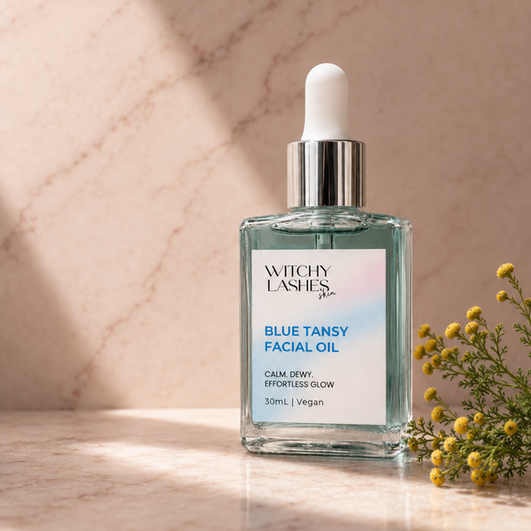 Witchy Lashes Blue Tansy Calming Facial Oil bottle on a beige fabric background
